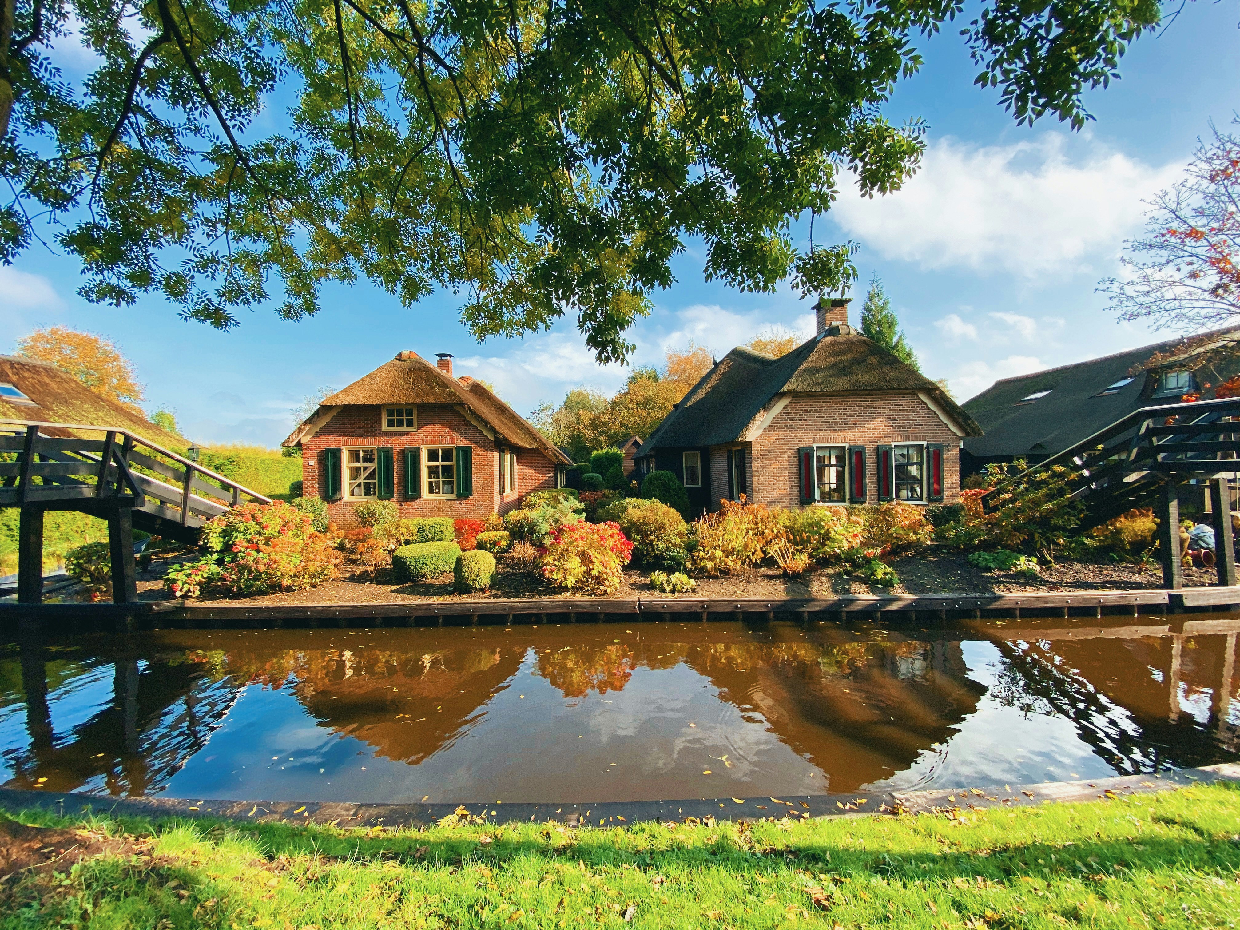 Image by Unsplash An illustrative photo of two brick houses near a river.