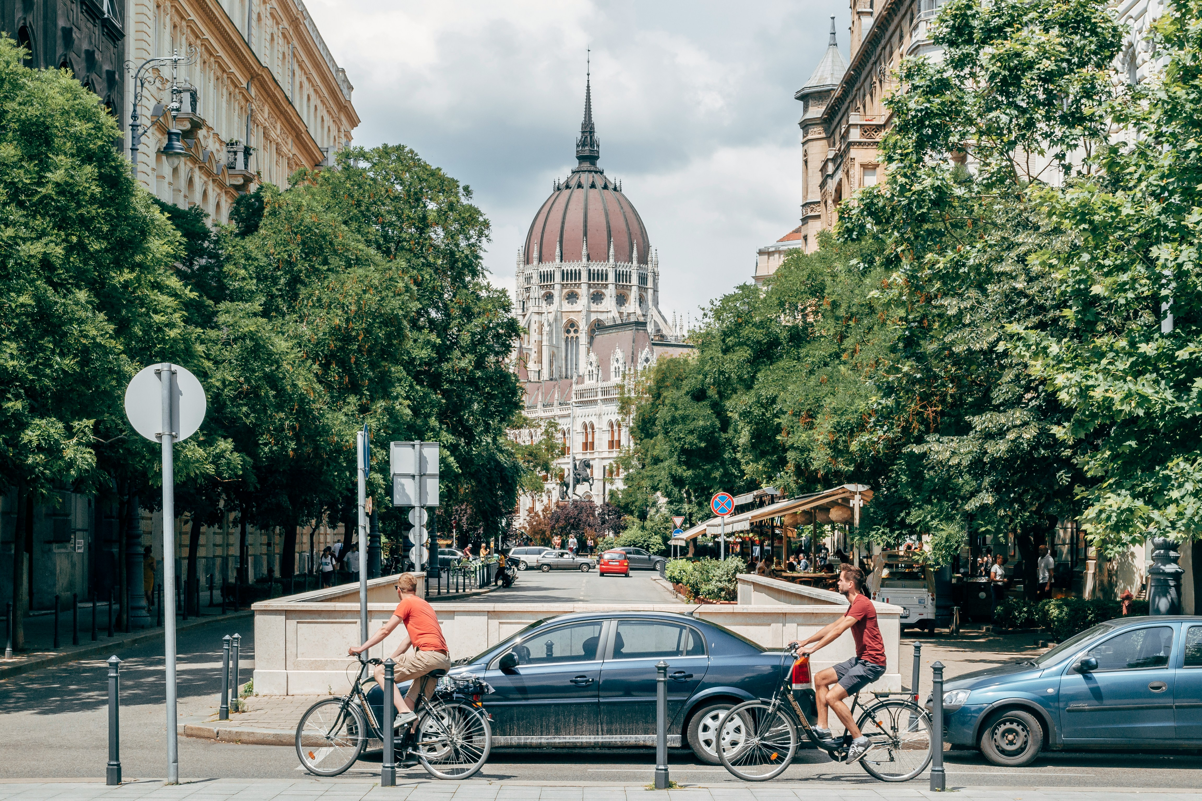 An illustrative photo of people walking on a sidewalk near cars and buildings.