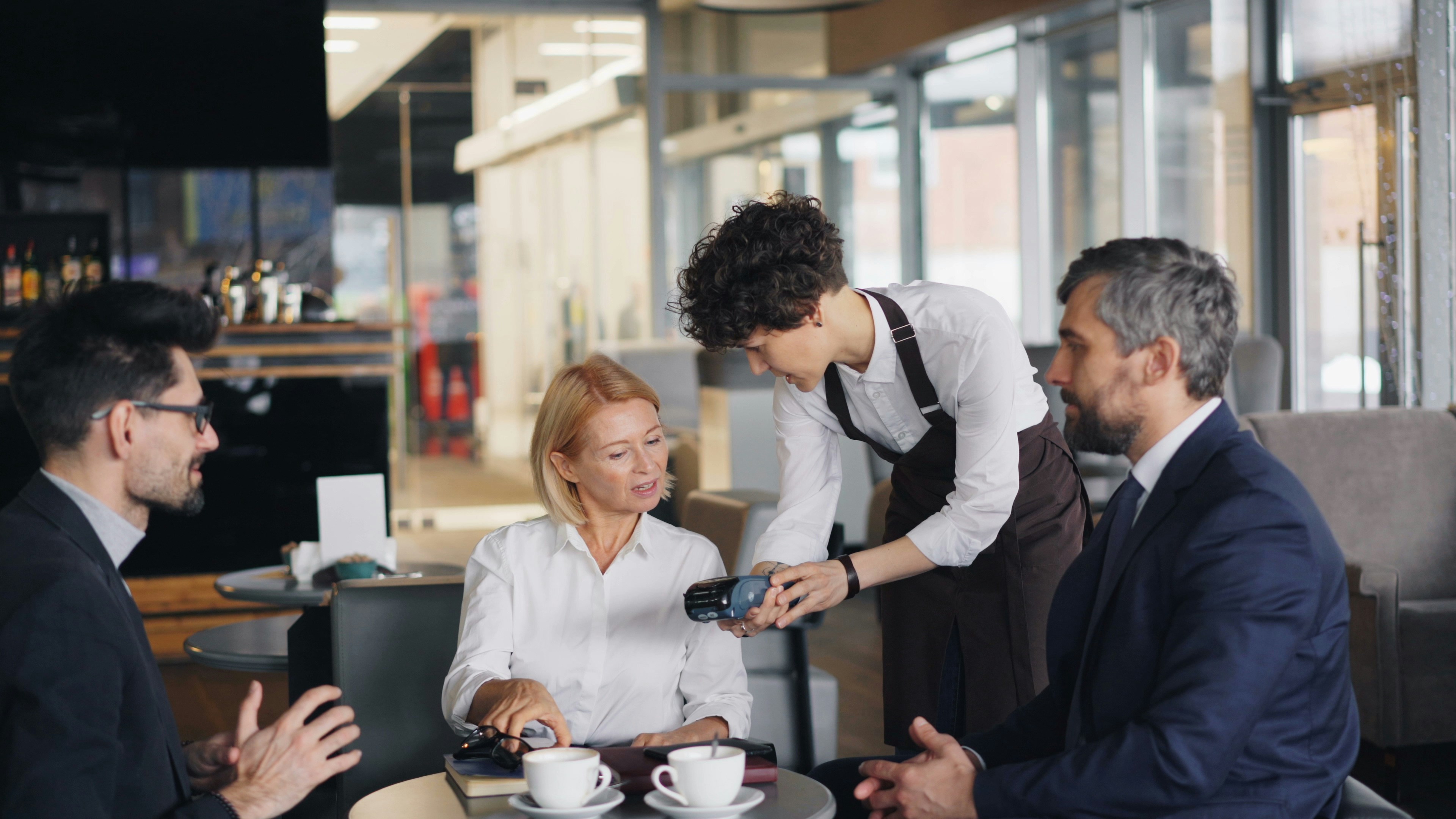 An illustrative photo of a waiter serving a table with three people.