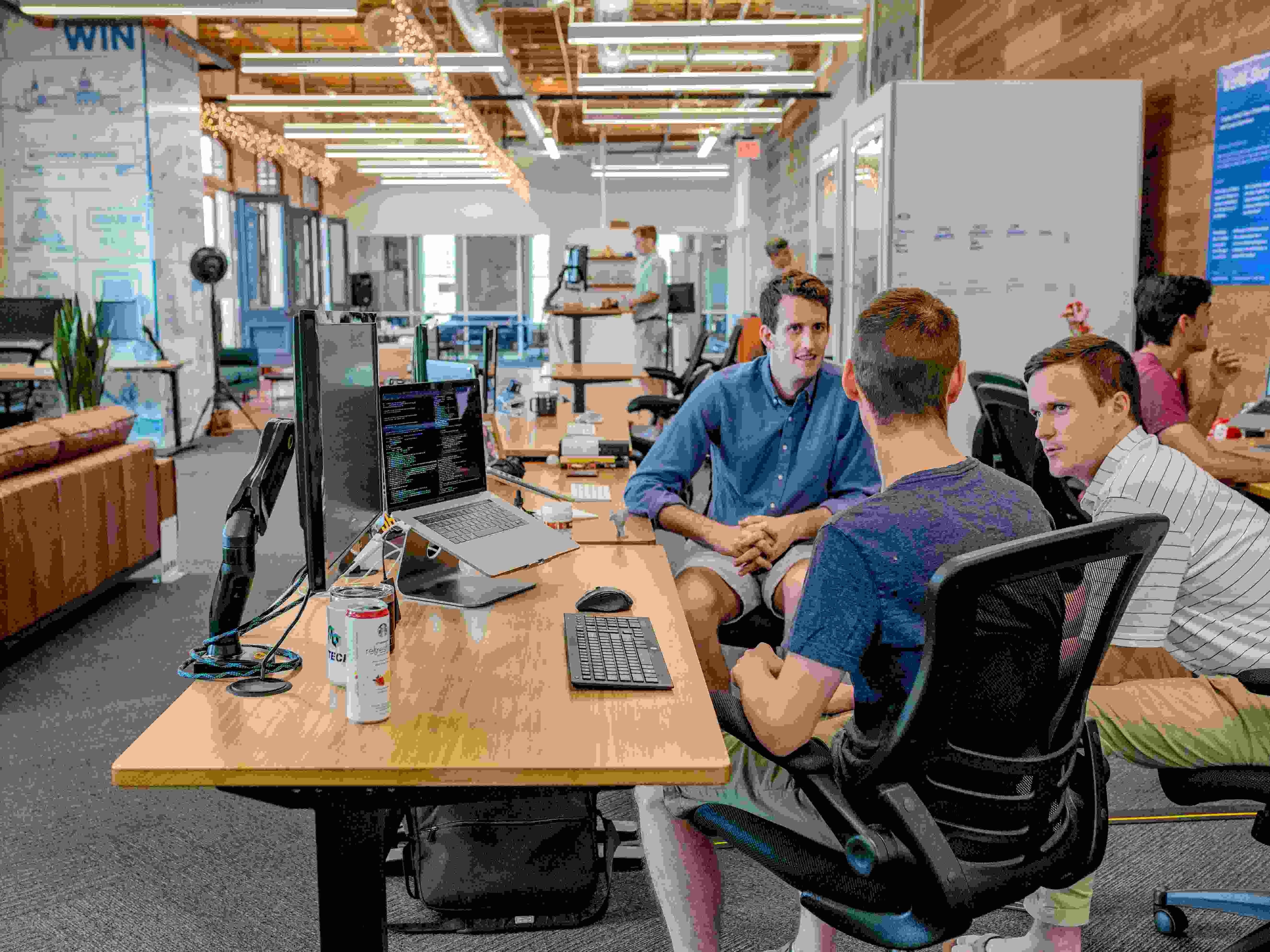 Photo by Unsplash An illustrative photo of three men sitting in the office and having a discussion.