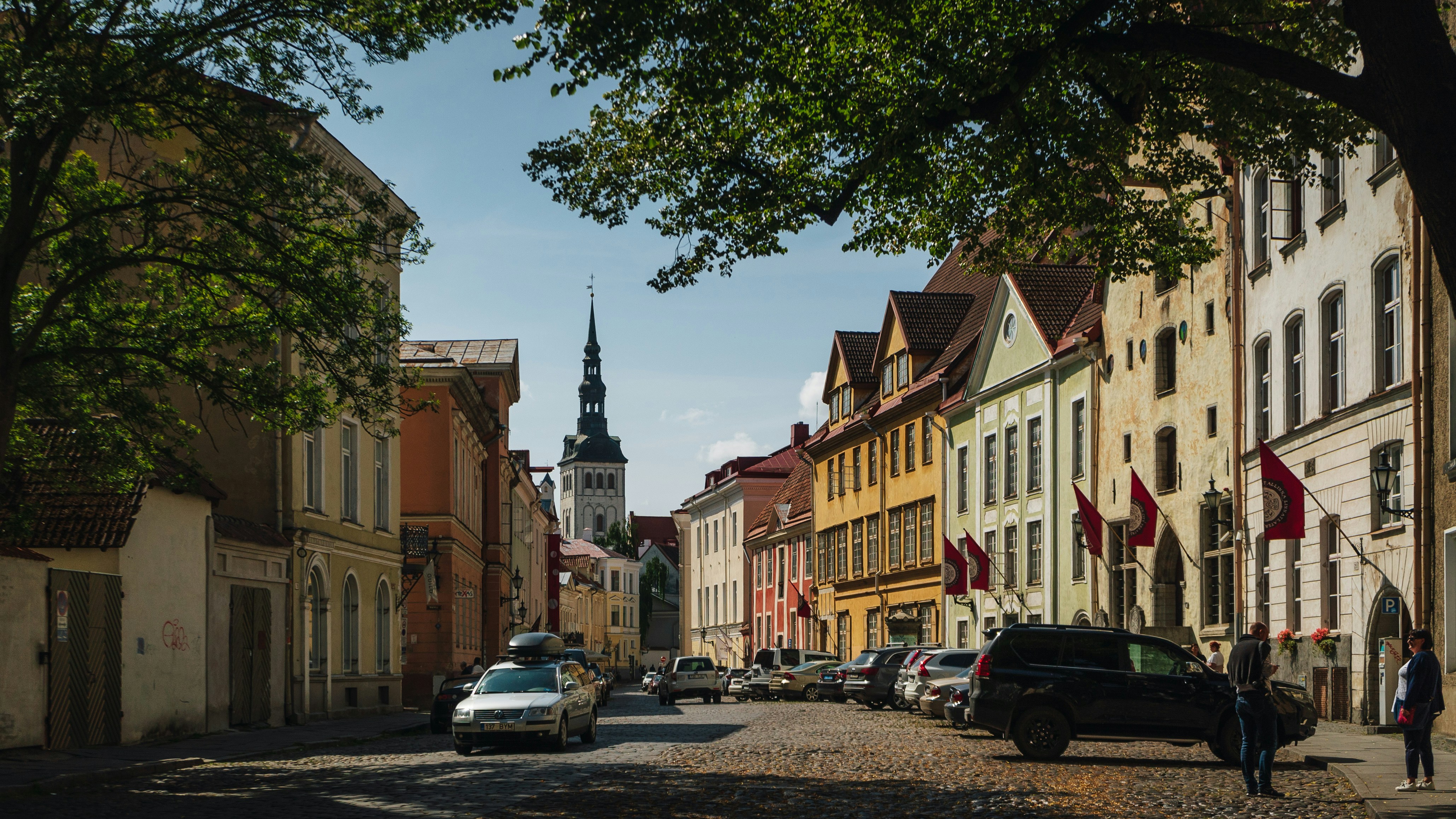 Photo by Unsplash An illustrative photo of a city street lined with parked cars and tall buildings.