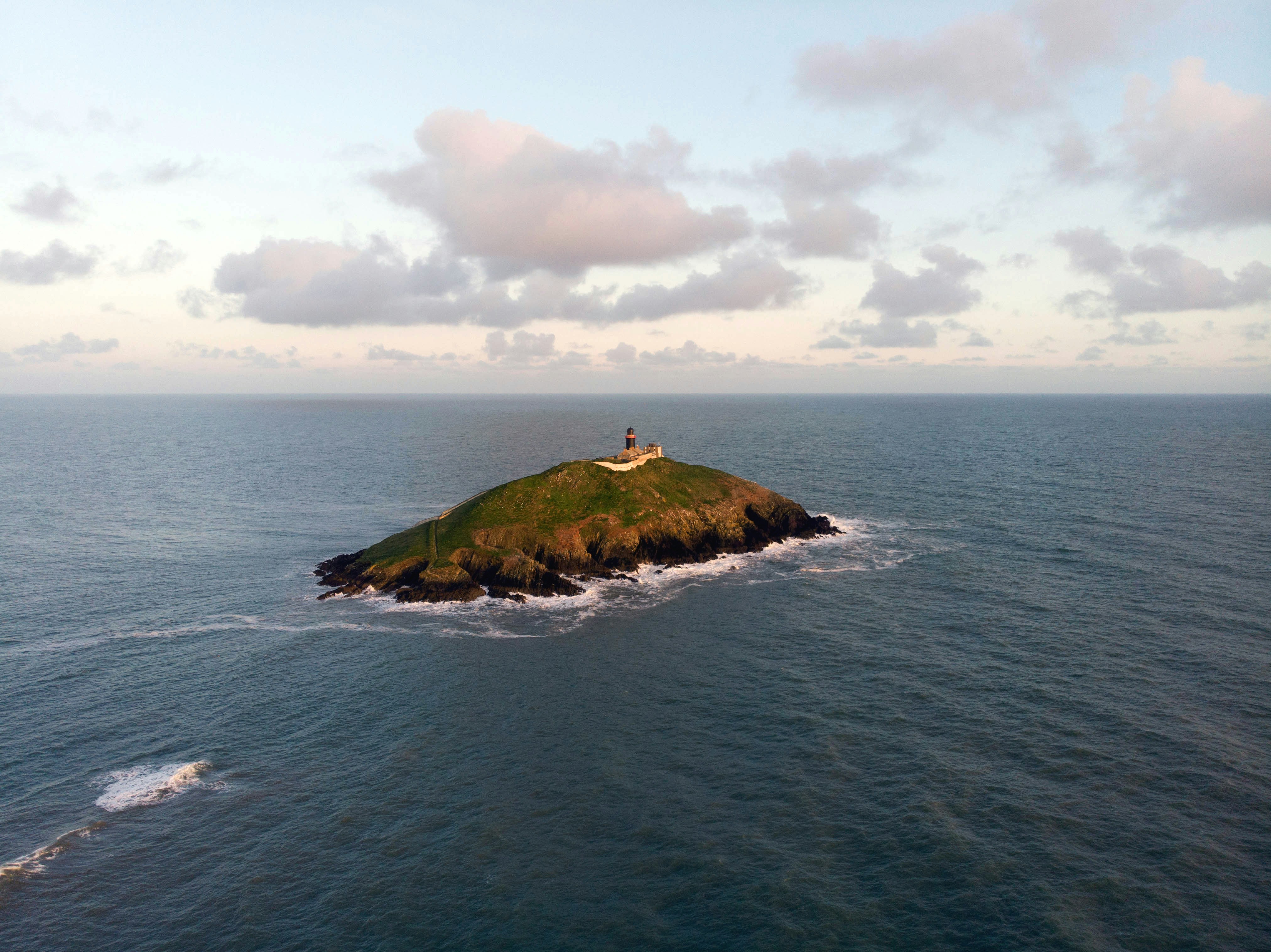 Photo by Unsplash An illustrative photo of a green and brown island under white clouds.