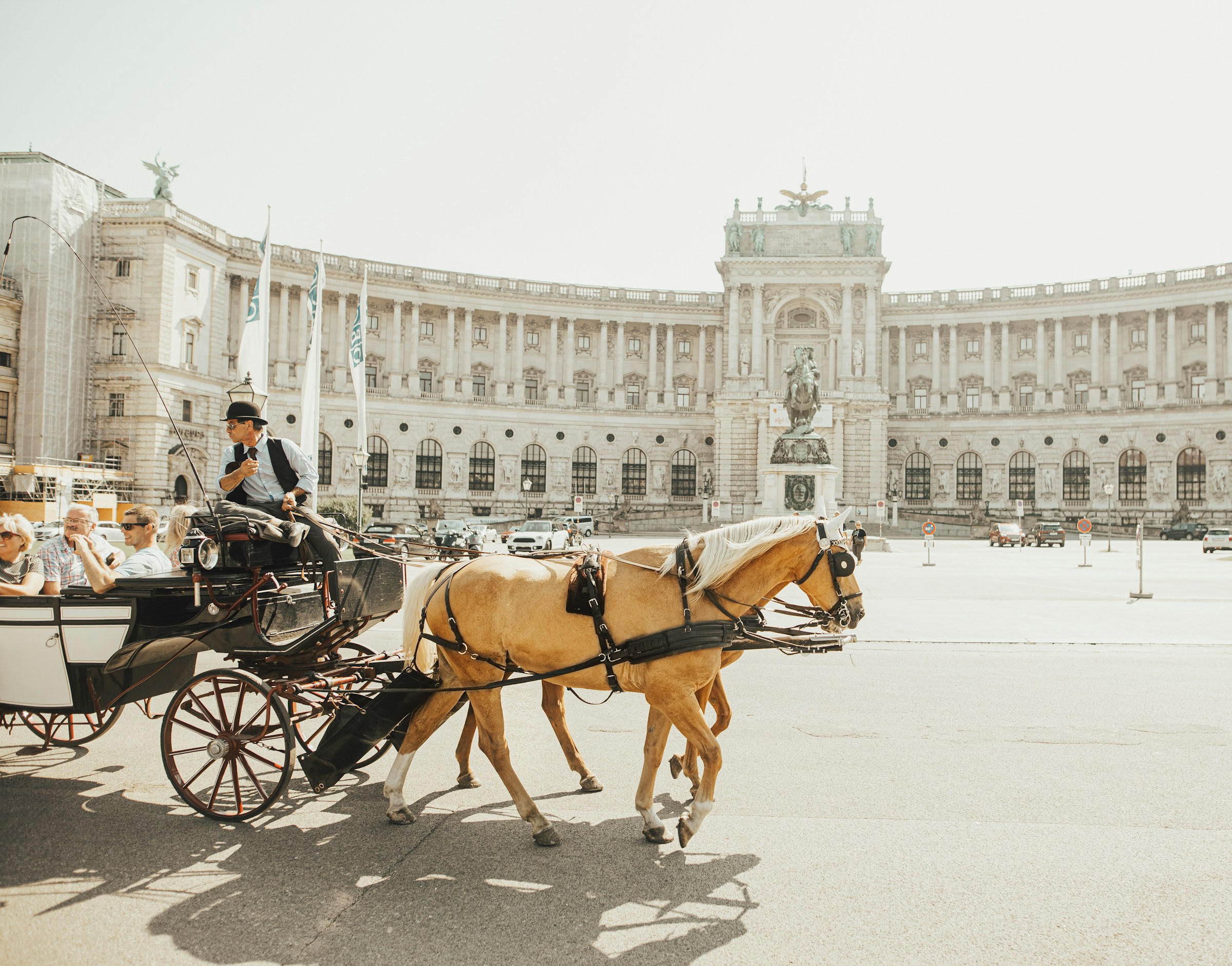Photo by Unsplash An illustrative photo of a man riding horse carriage near big white building in Vienna