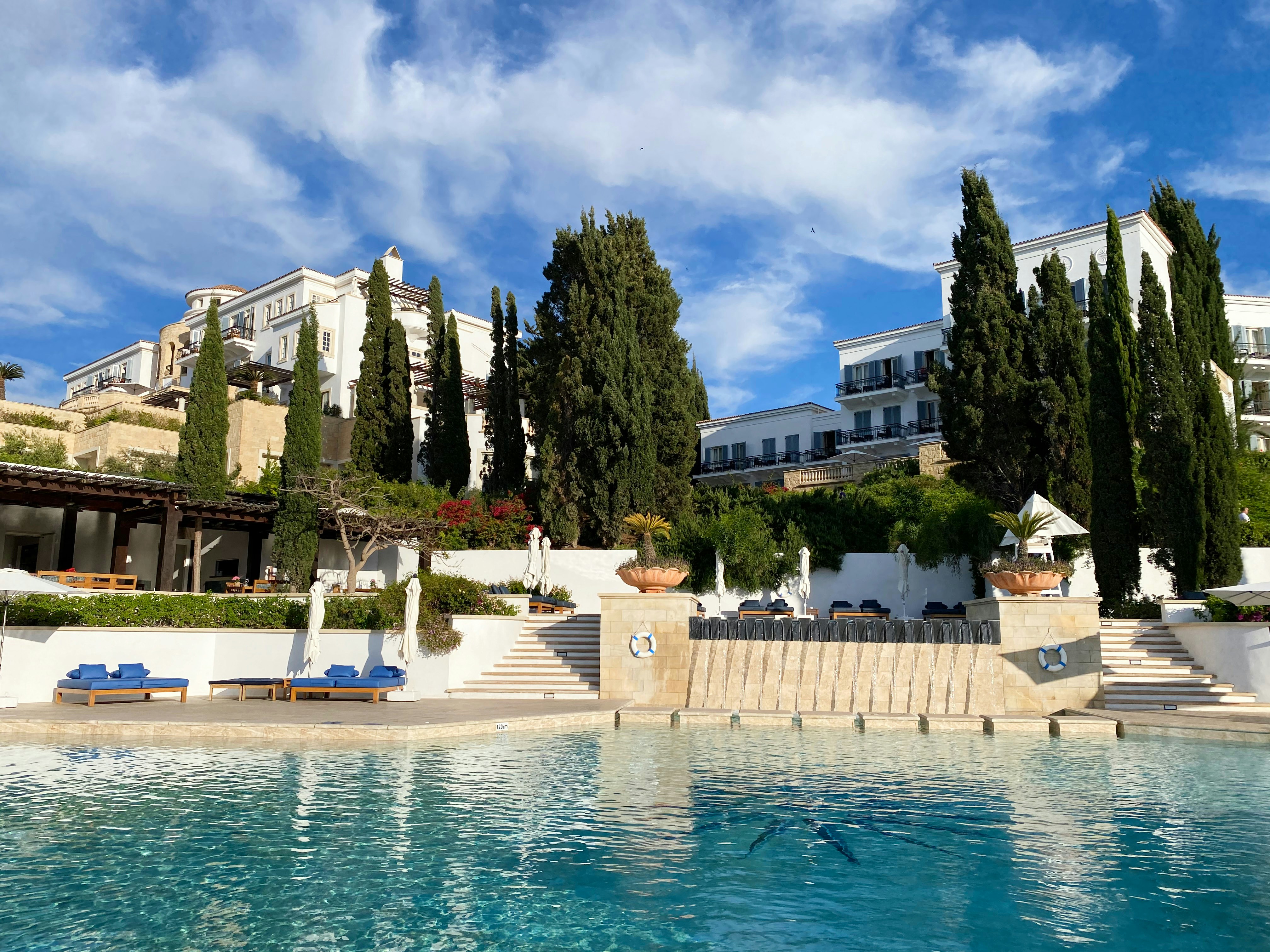 An illustrative photo of a white concrete building near a swimming pool.