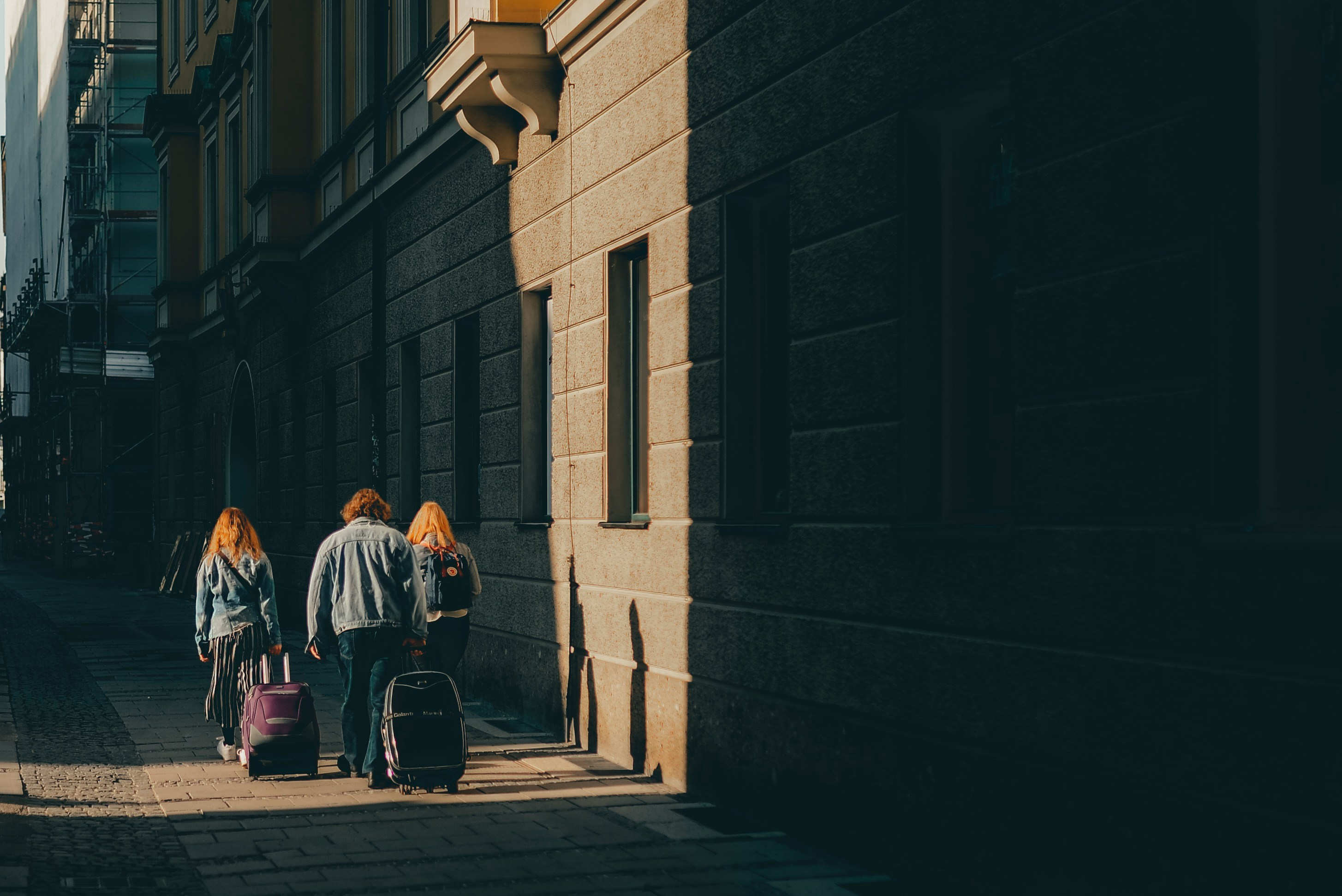 An illustrative photo of three people walking on the sidewalk near the walls.