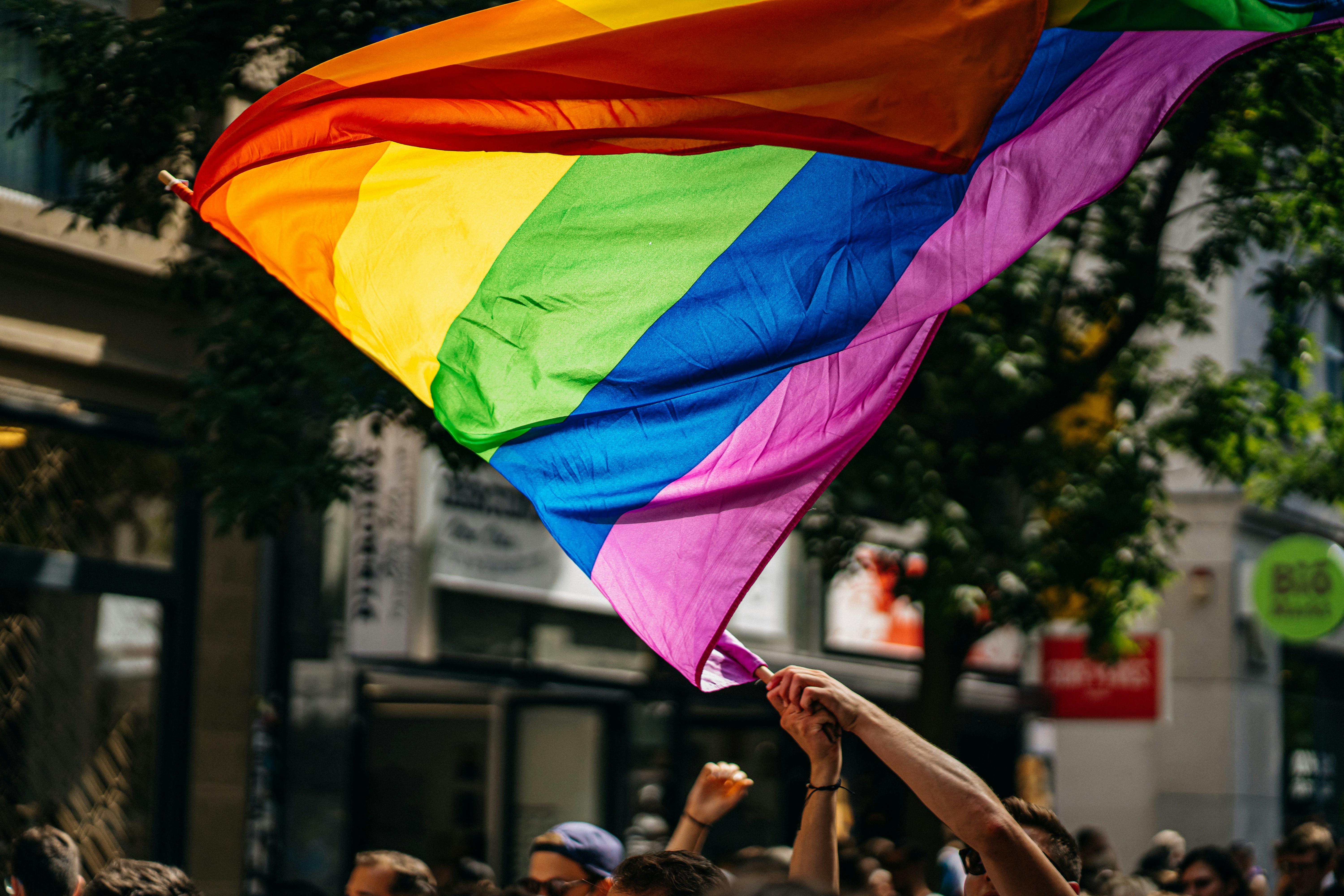 An illustrative photo of a person waving an LGBTQ+ flag.