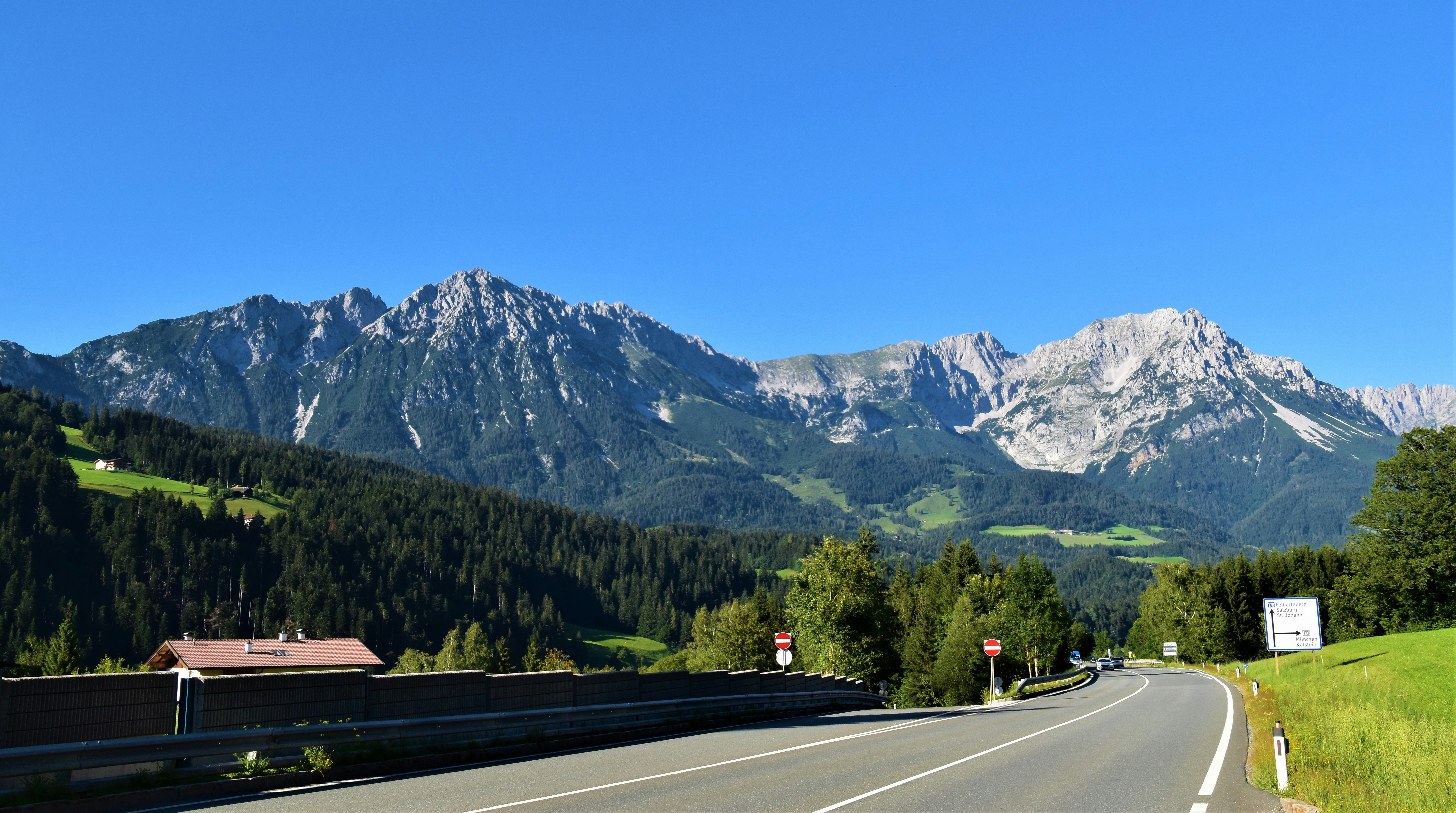Photo by Unsplash An illustrative photo of a road near green trees and mountains under blue sky.