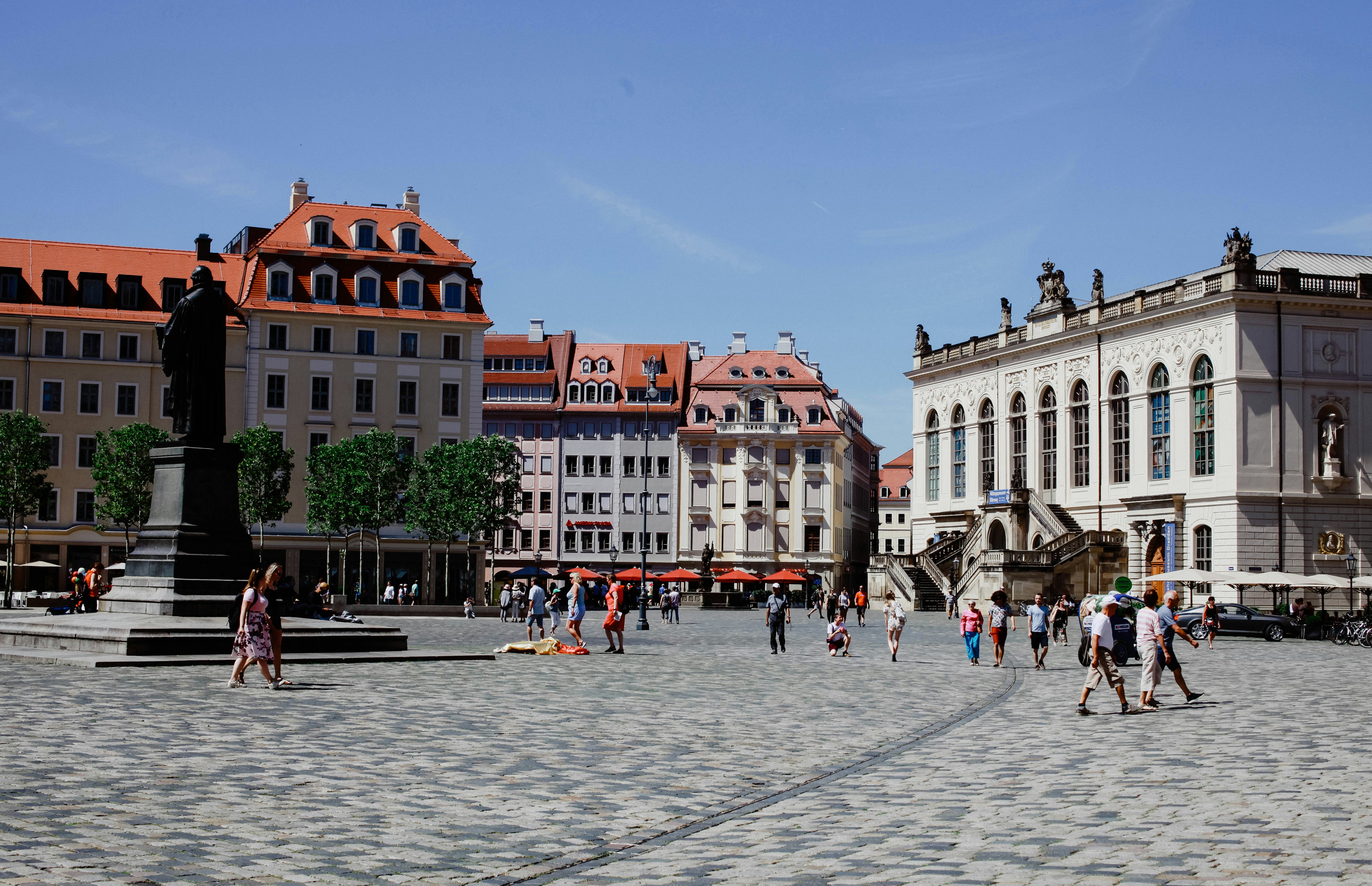 An illustrative photo of a group of people walking around a city square.