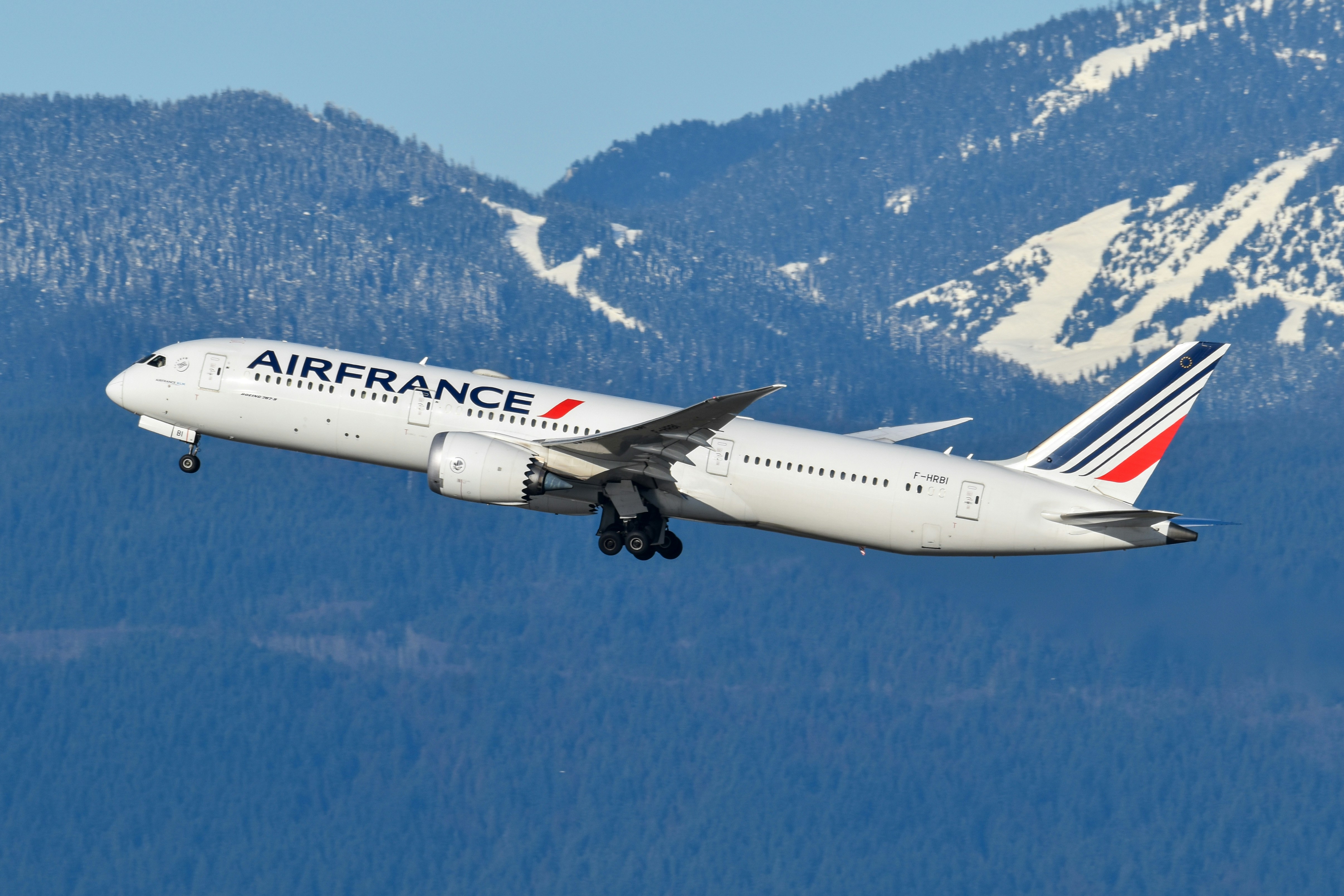 An illustrative photo of an airplane flying over a mountain range.