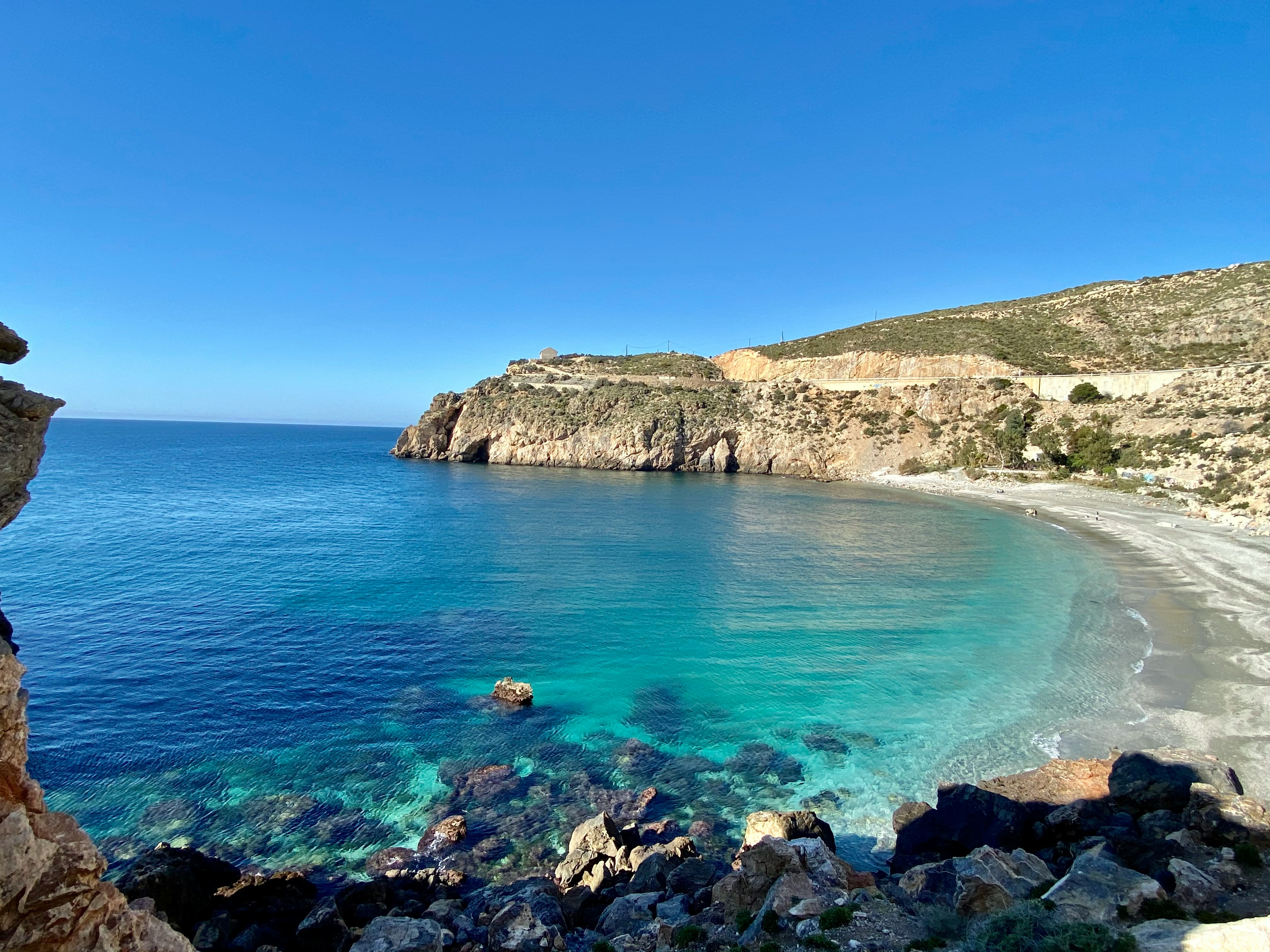 An illustrative photo of a brown rocky mountain beside blue sea.