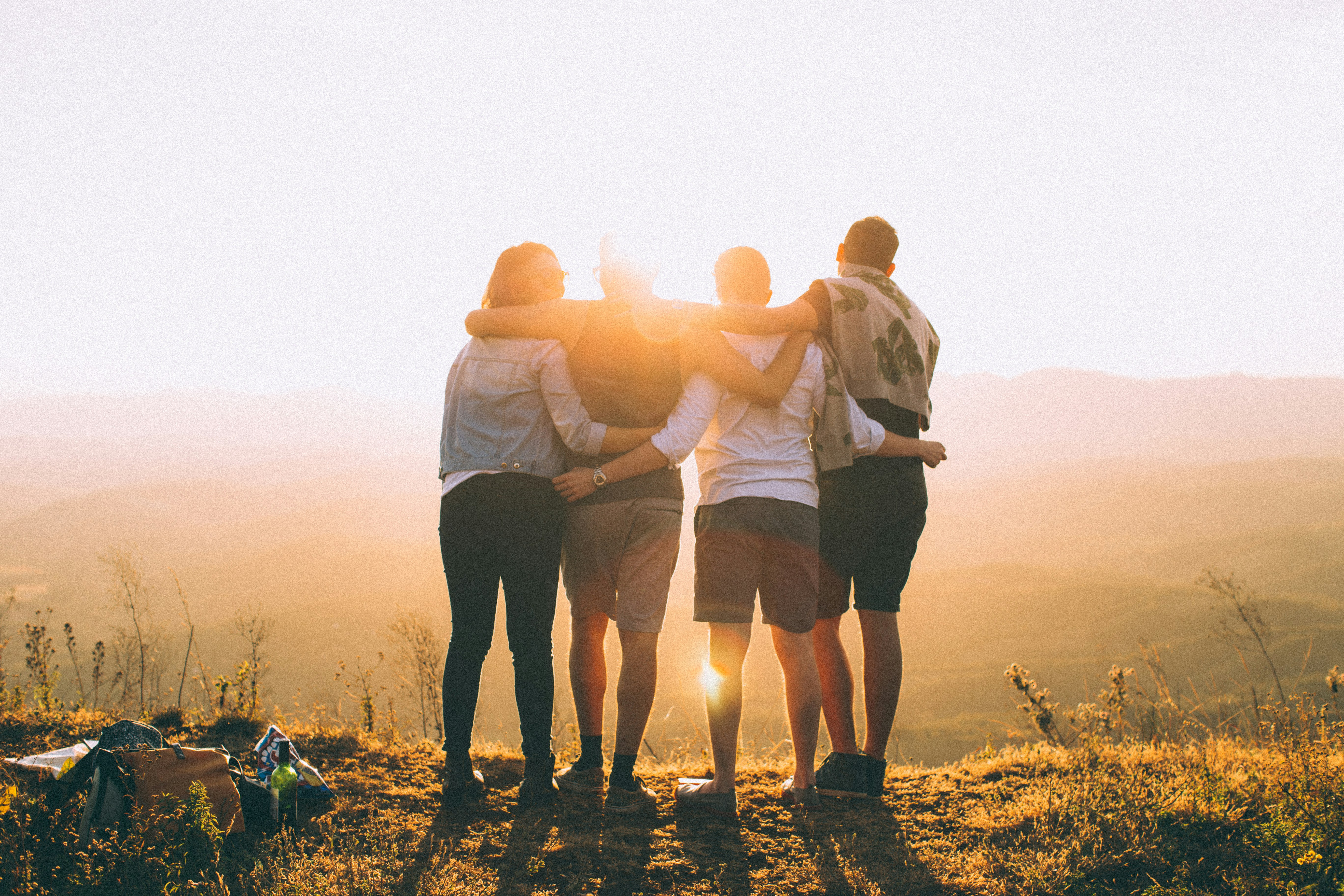 A group of friends hugging on a hill by sunset