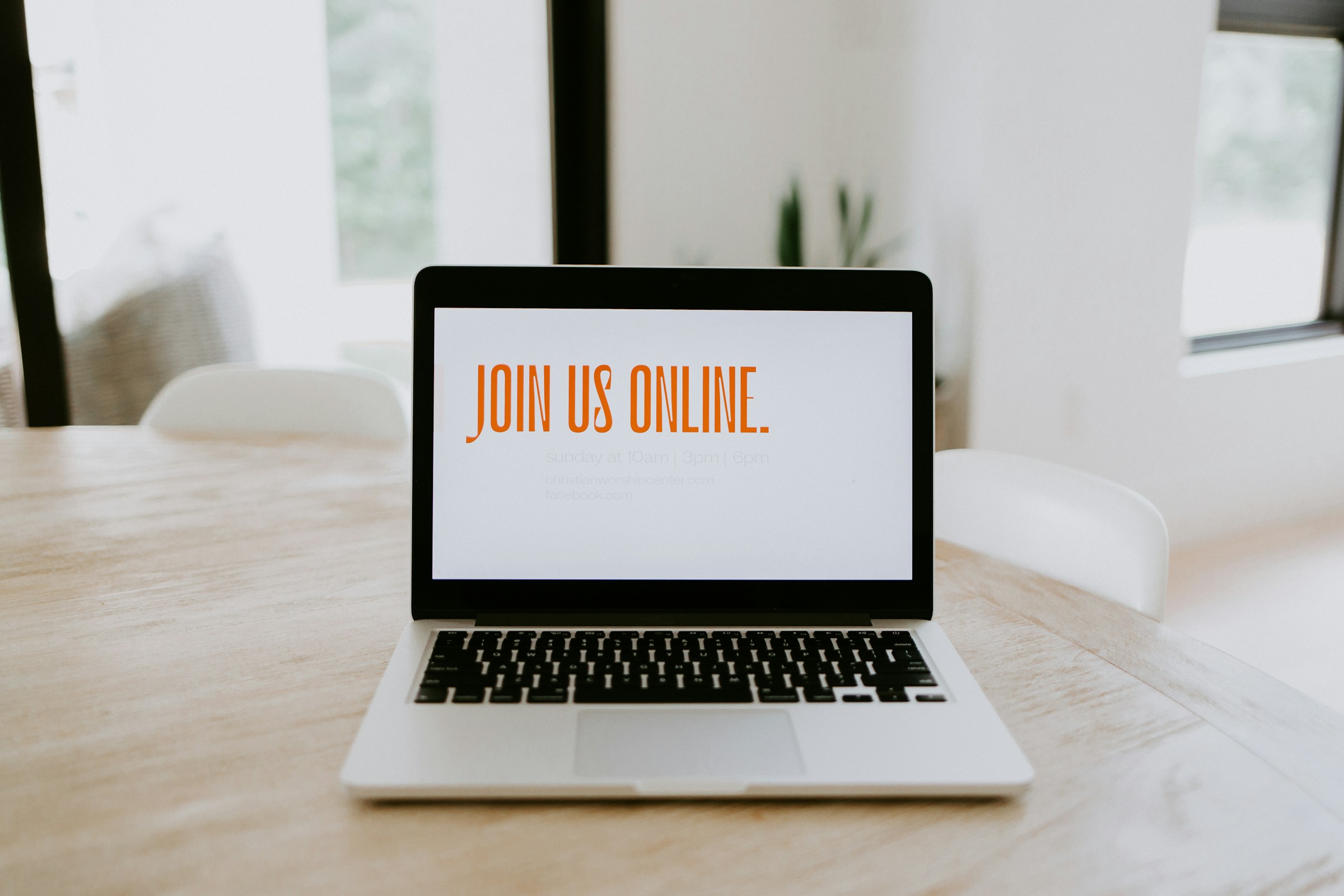 Laptop on a table displaying the message “Join us online,” suggesting a virtual event or online meeting invitation.
