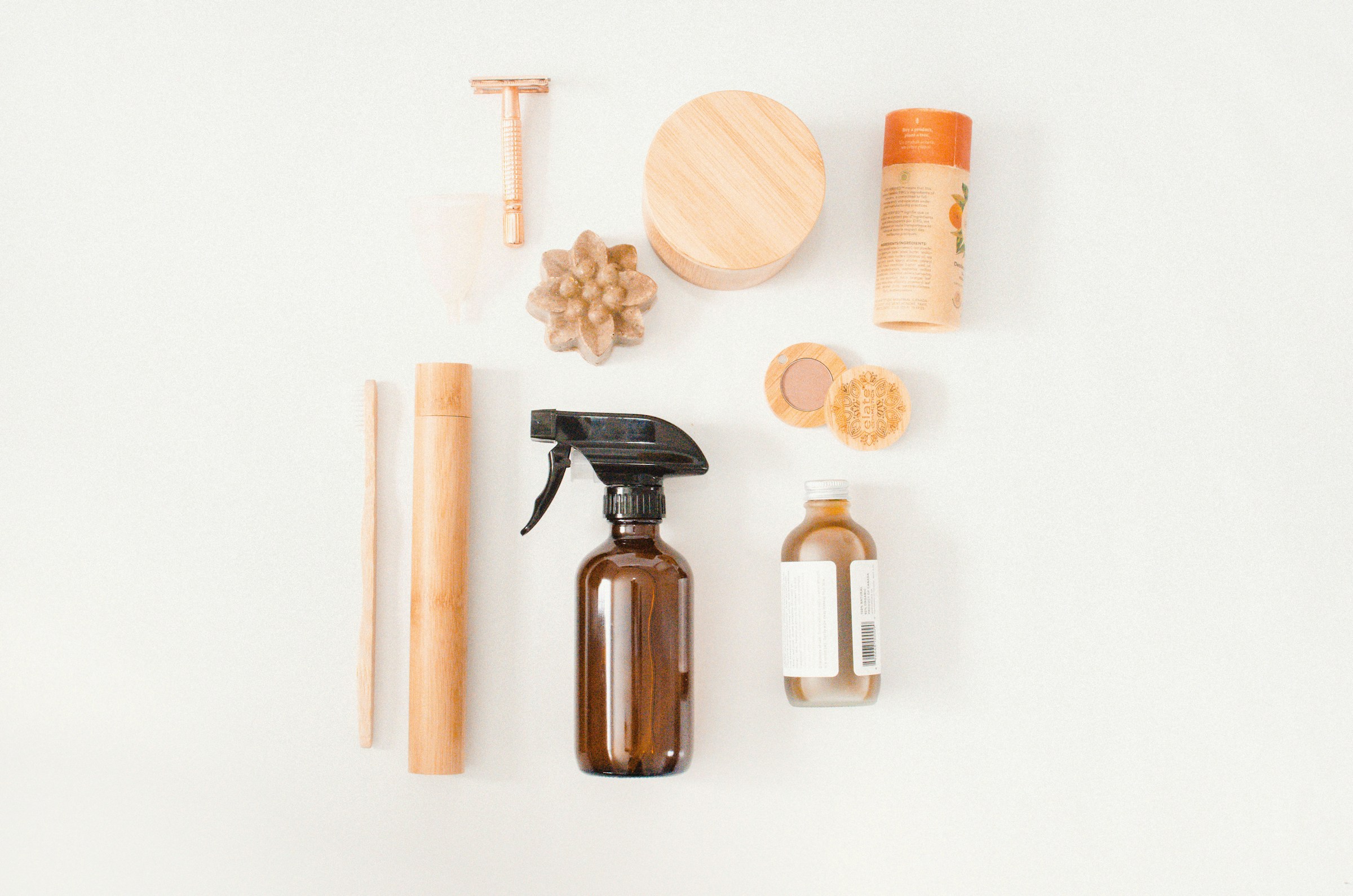 A flat lay of sustainable personal care items, including reusable containers, wooden accessories, and glass bottles.