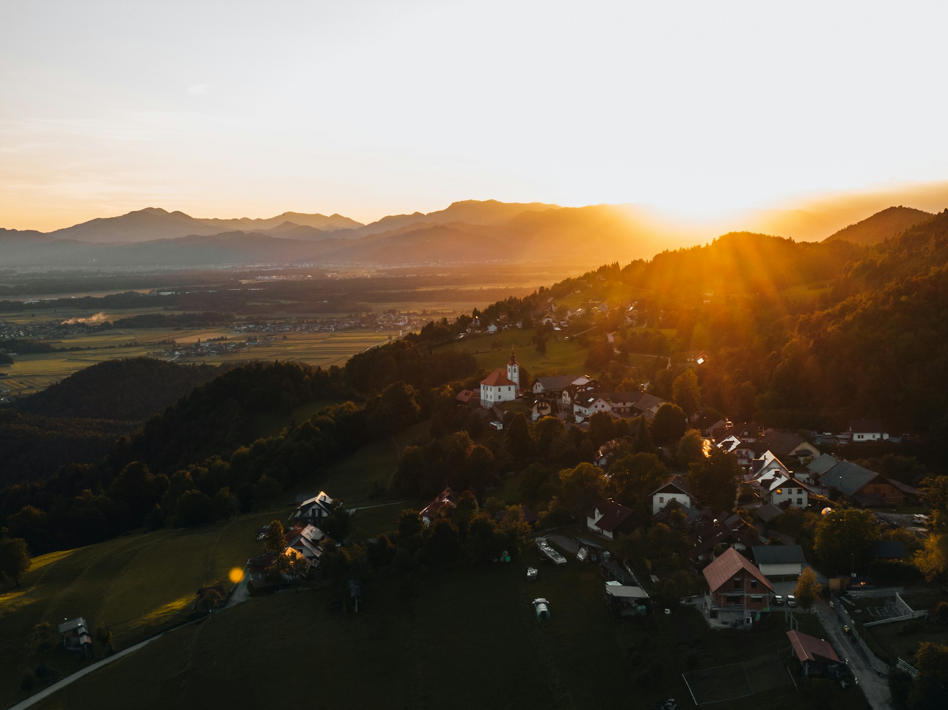 sunset-over-a-small-village-nestled-in-rolling-hills