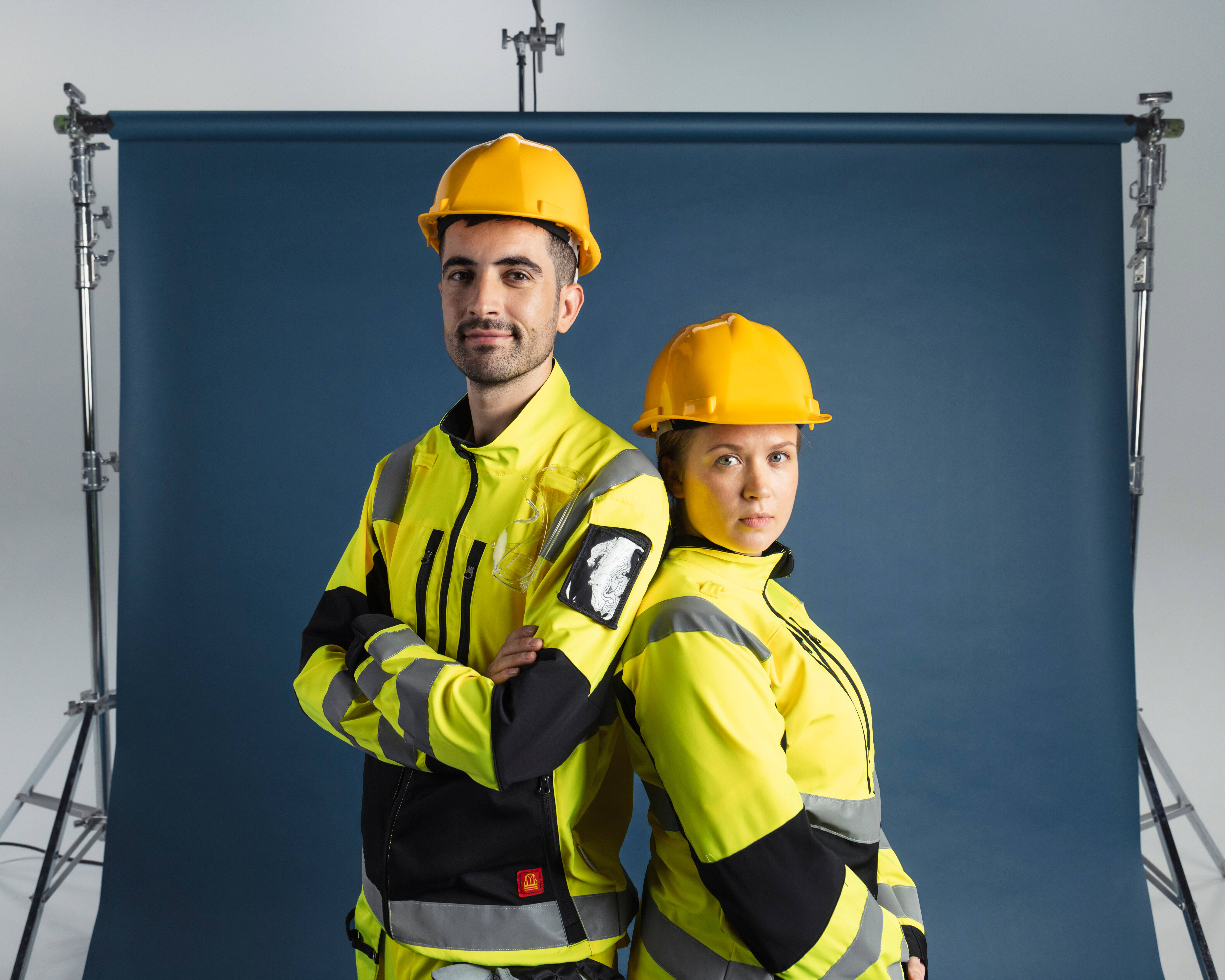 Two construction workers wearing yellow safety jackets and hard hats.