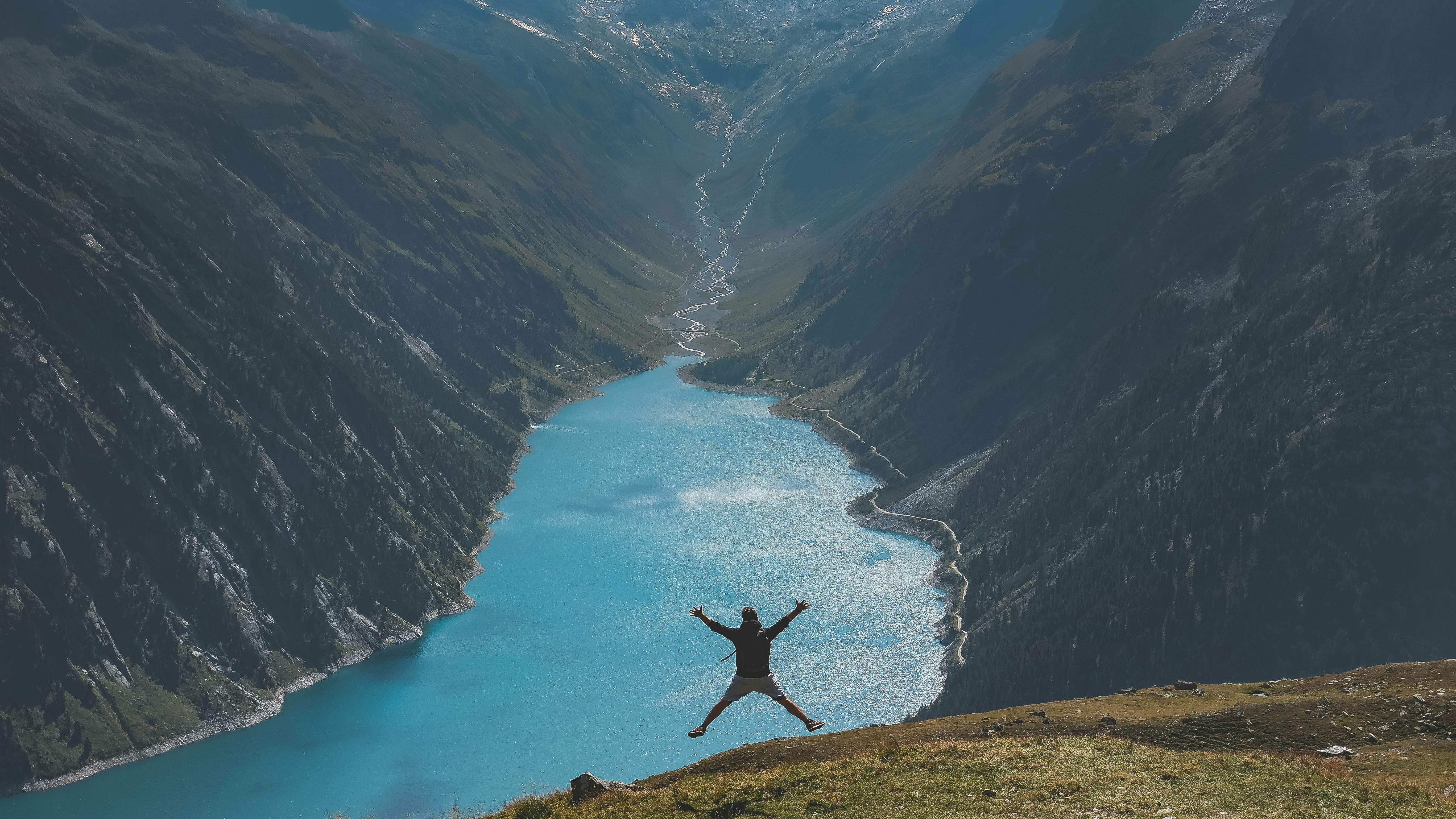 Person jumping on a hill overlooking a river valley