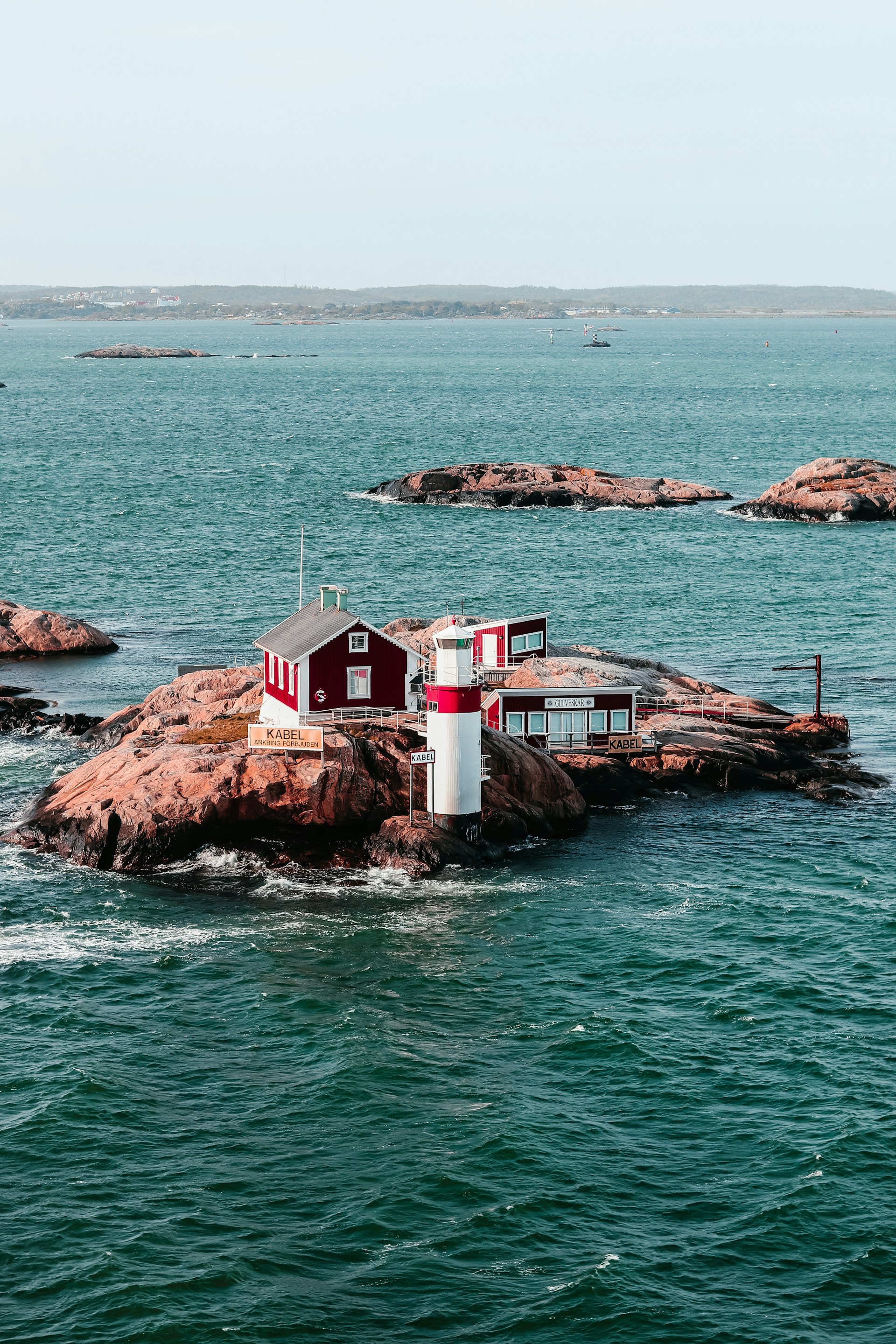 a-red-and-white-house-sitting-on-top-of-a-rock-in-the-ocean