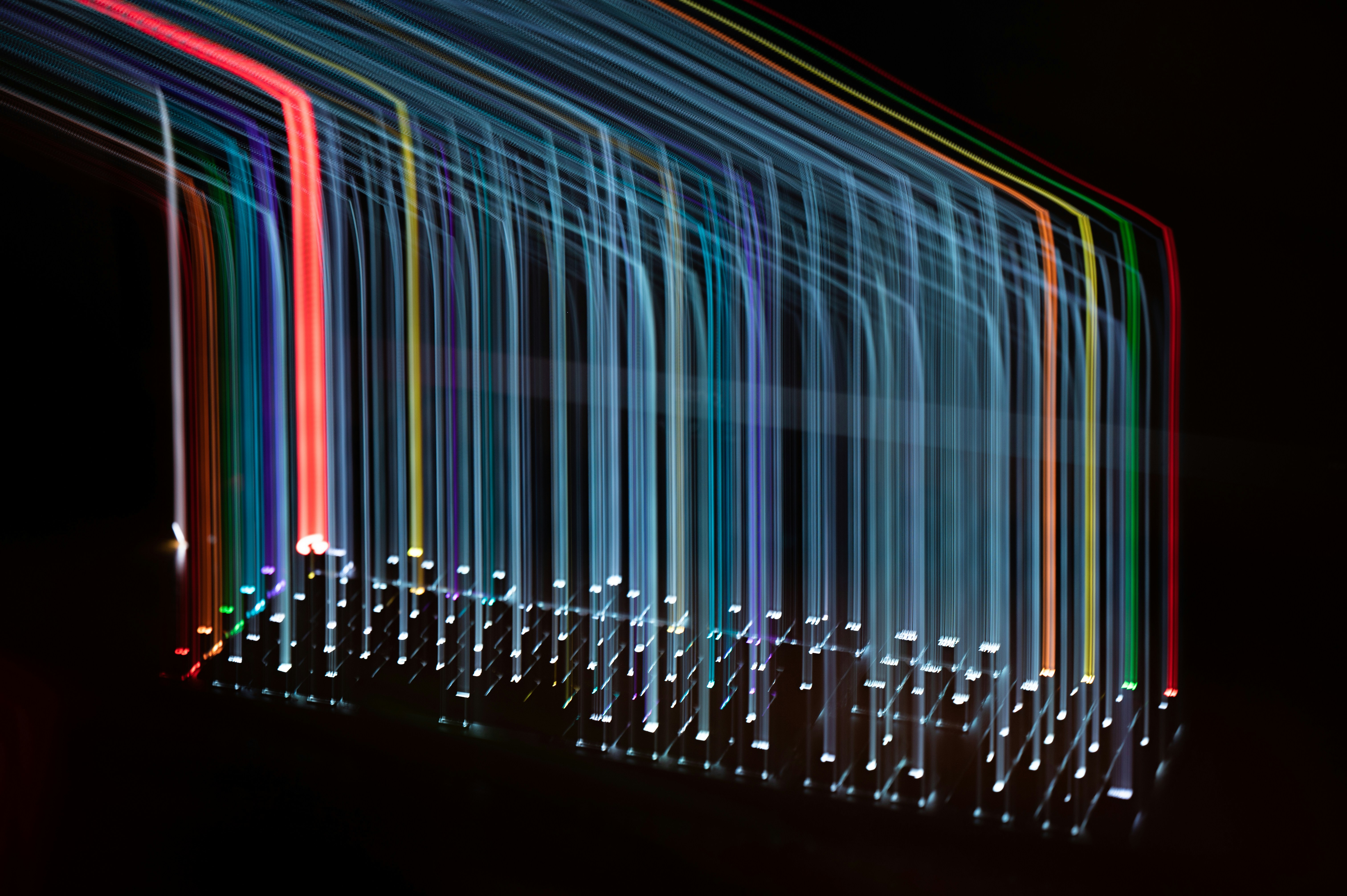 Abstract light trails forming colorful vertical lines against a dark background.