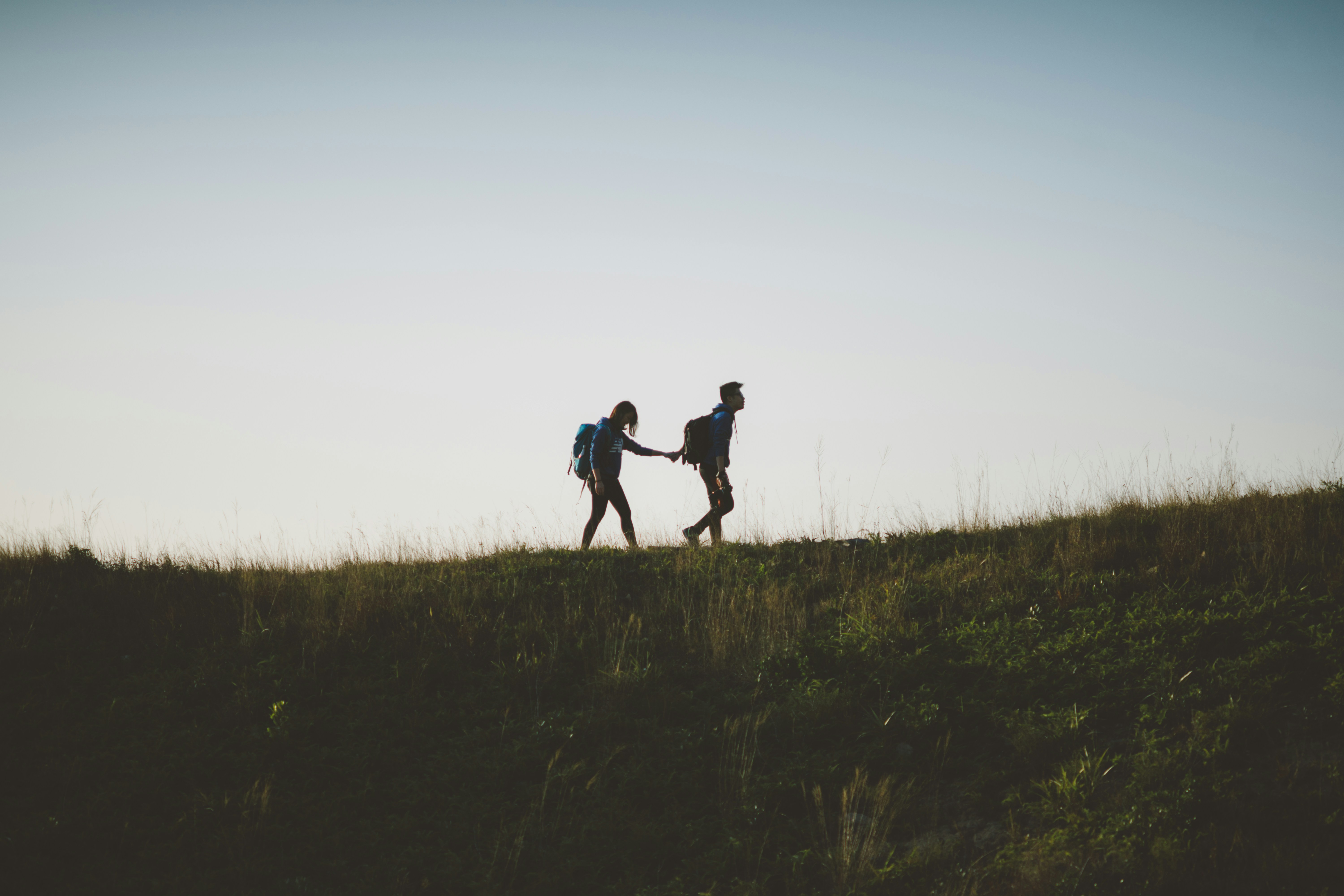 couple-walking-on-hill-while-holding-during-daytime