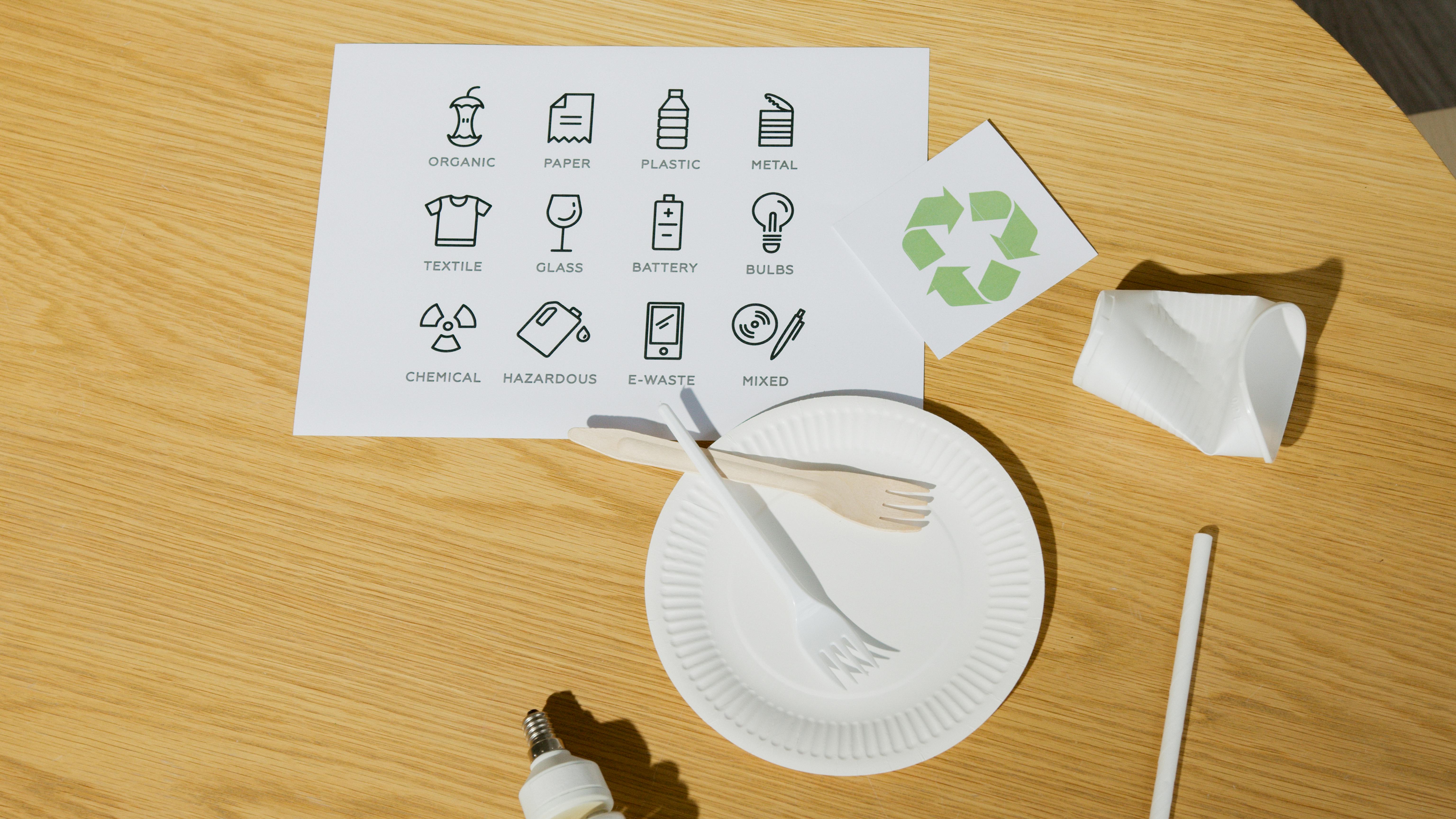 Paper forks on paper plate near card with recycling pictographs.