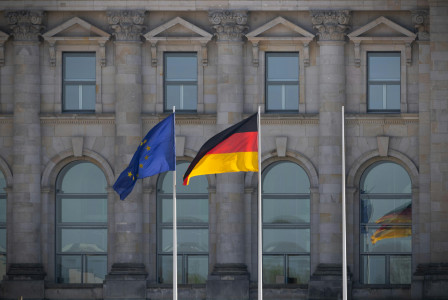 German and EU flags flying in front of the Reichstag building in Berlin, Germany.