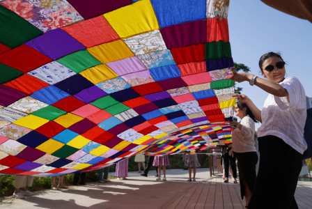Colourful patchwork quilt held by smiling participants.