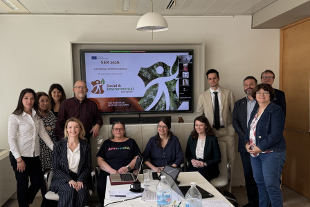 Group photo of participants at a meeting room in front of a screen. 