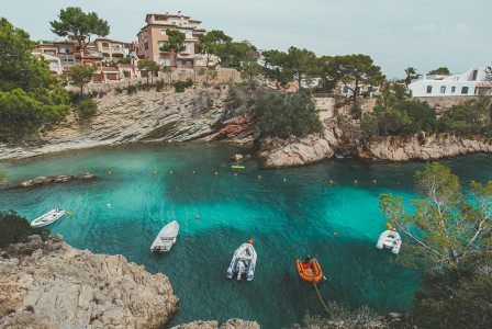 people-in-white-and-orange-boat-on-water-near-brown-rock-formation-during-daytime