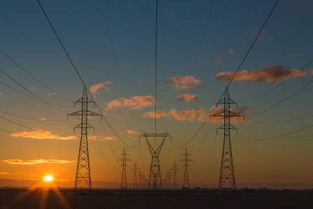 A graphic presenting high-voltage power lines stretch across an open landscape at sunset.