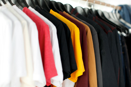 Clothes in various colors hanging on a rack.