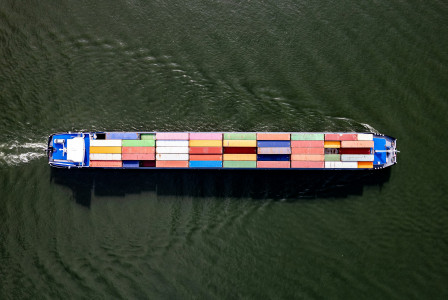 The picture presents a cargo ship carrying colorful shipping containers on the water.