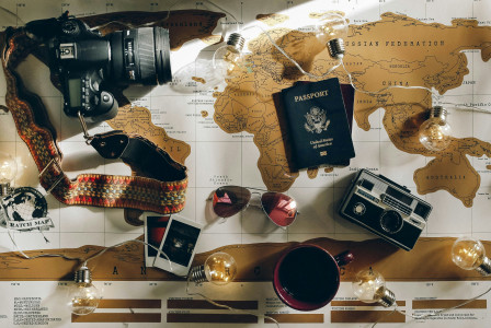 The picture presents travel items arranged on a world map, including a camera and passport.