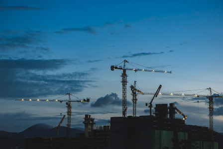 A photo presents a construction cranes.