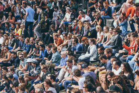 A picture presents a large crowd of people sitting together outdoors.