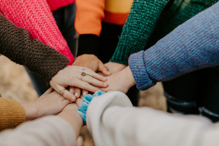 Photo presenting a group of hands stacked together, symbolizing teamwork and collaboration.