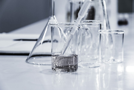 Laboratory glassware on a lab bench with a pipette in a transparent beaker containing a clear liquid.