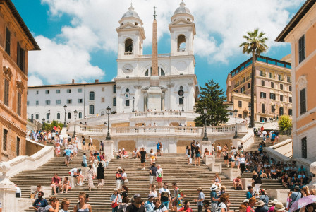 A picture presents tourists gathered on a large historic staircase.
