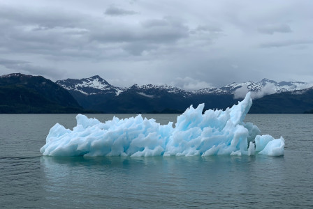 The picture presents an iceberg on the water.
