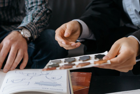 Two individuals discussing design samples and color swatches at a table, focusing on collaboration