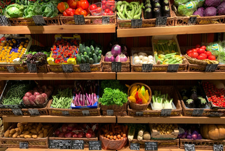The picture presents a grocery store with a wide variety of fresh fruits and vegetables.