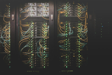Photo presenting server racks with illuminated network cables and data center equipment.