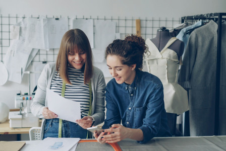 Two designers collaborate, reviewing plans with smiles.