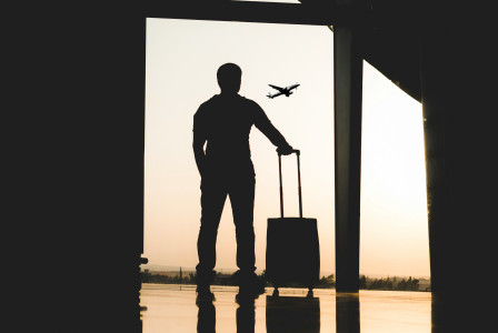 A picture presents a traveler with luggage at an airport.
