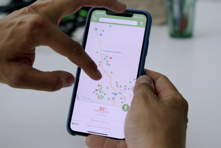 Hands holding a smartphone displaying a map of textile collection points.