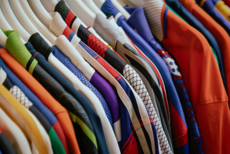 The photo presents colourful clothes on hangers.