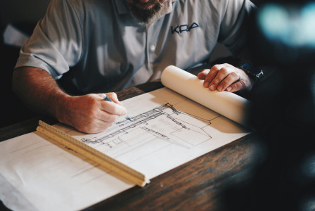 The picture describes an architect reviewing building plans.