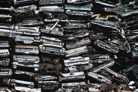 The photo presents a pile of old cars.