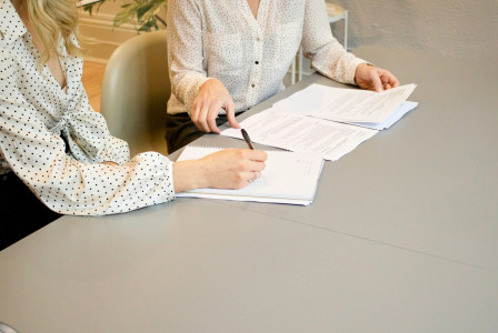 The photo presents two people reviewing documents together.