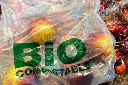 The photo presents apples in a compostable plastic bag.