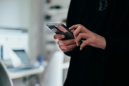 The photo presents a person using a smartphone.
